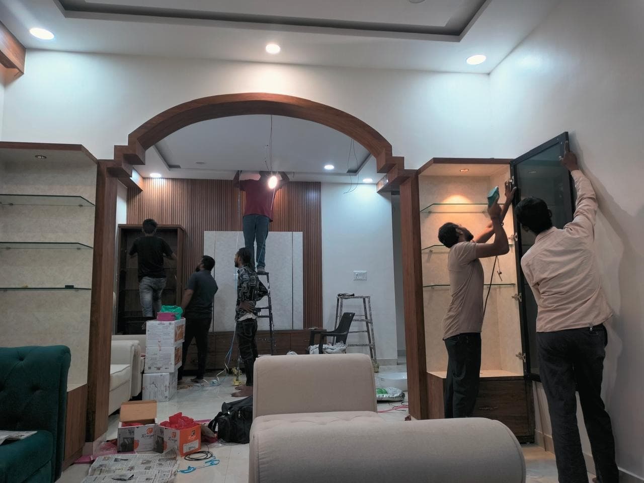 Turnkey carpentry team installing stepped arch and illuminated cabinetry